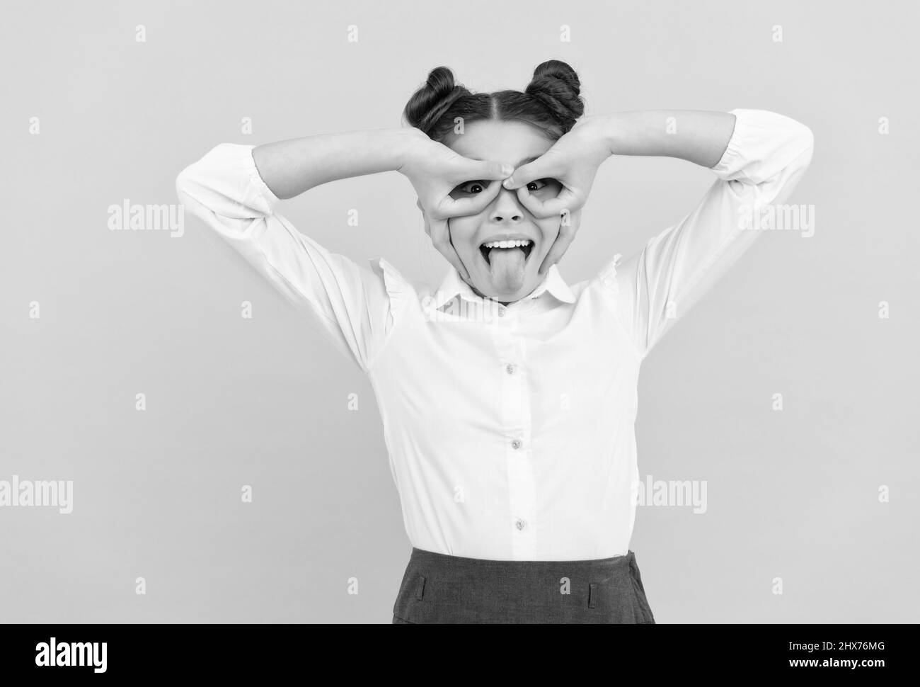 Felice età scolastica bambino fare dita maschera supereroe attaccando lingua fuori sfondo blu, giocando Foto Stock