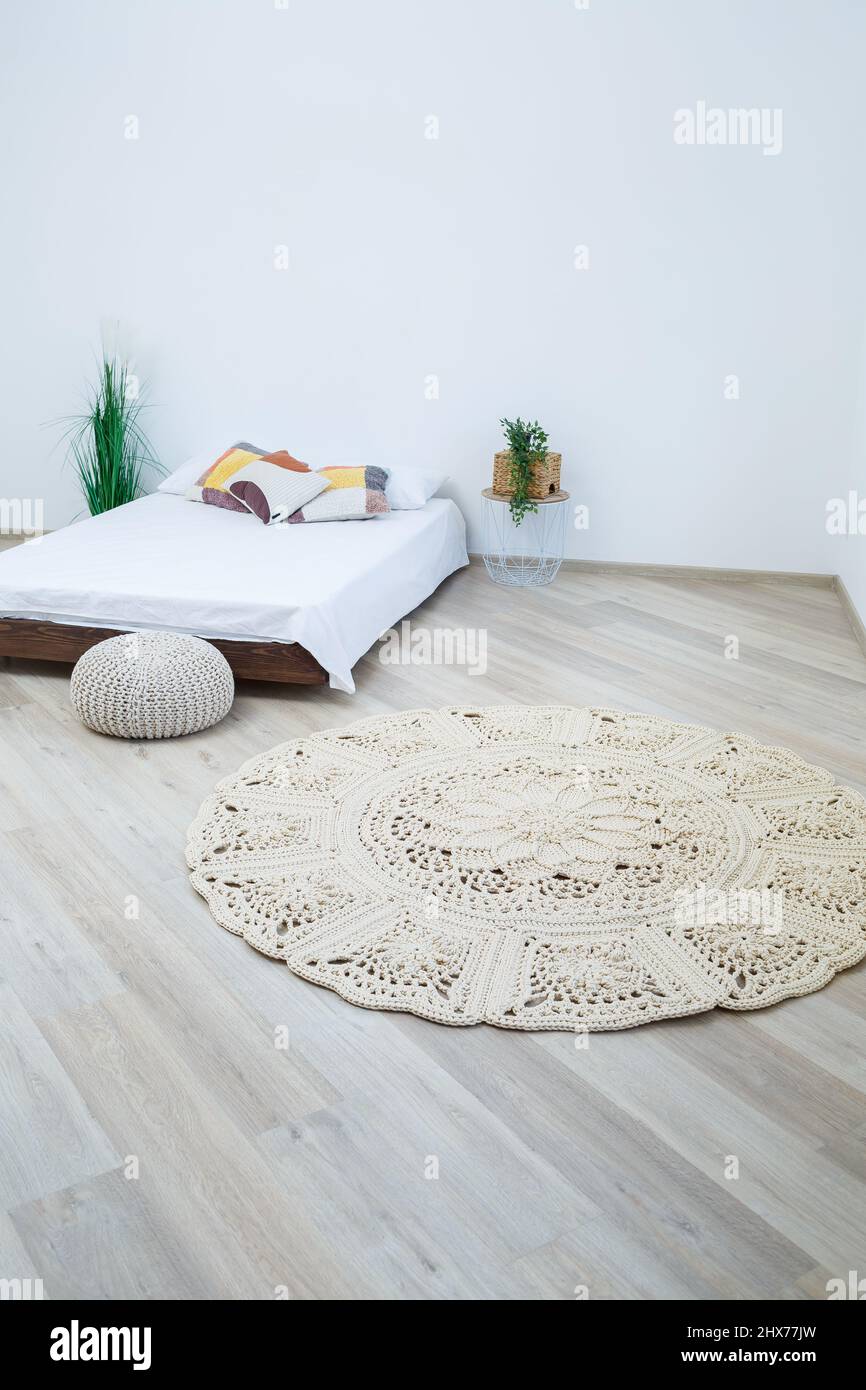 Carino modello fatto in casa a maglia di fili spessi fatti a mano: Un  tappeto fatto a mano fatto di fili beige si trova nella camera da letto  vicino al letto, l'arte