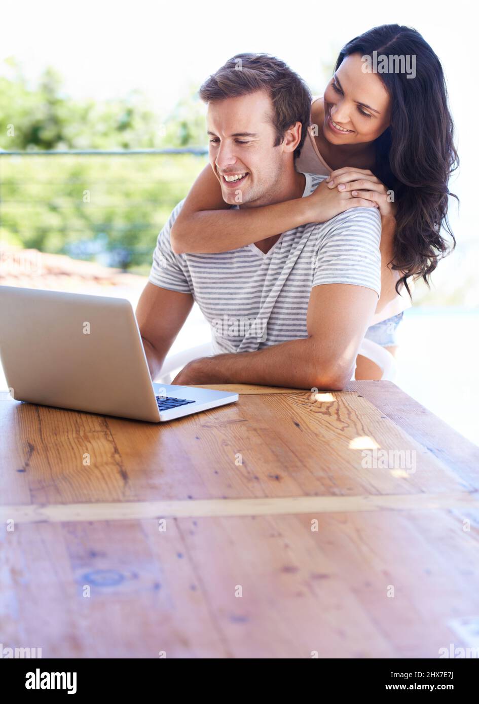 Navigare sul Web all'esterno. Una giovane coppia che usa il proprio computer portatile sul patio. Foto Stock