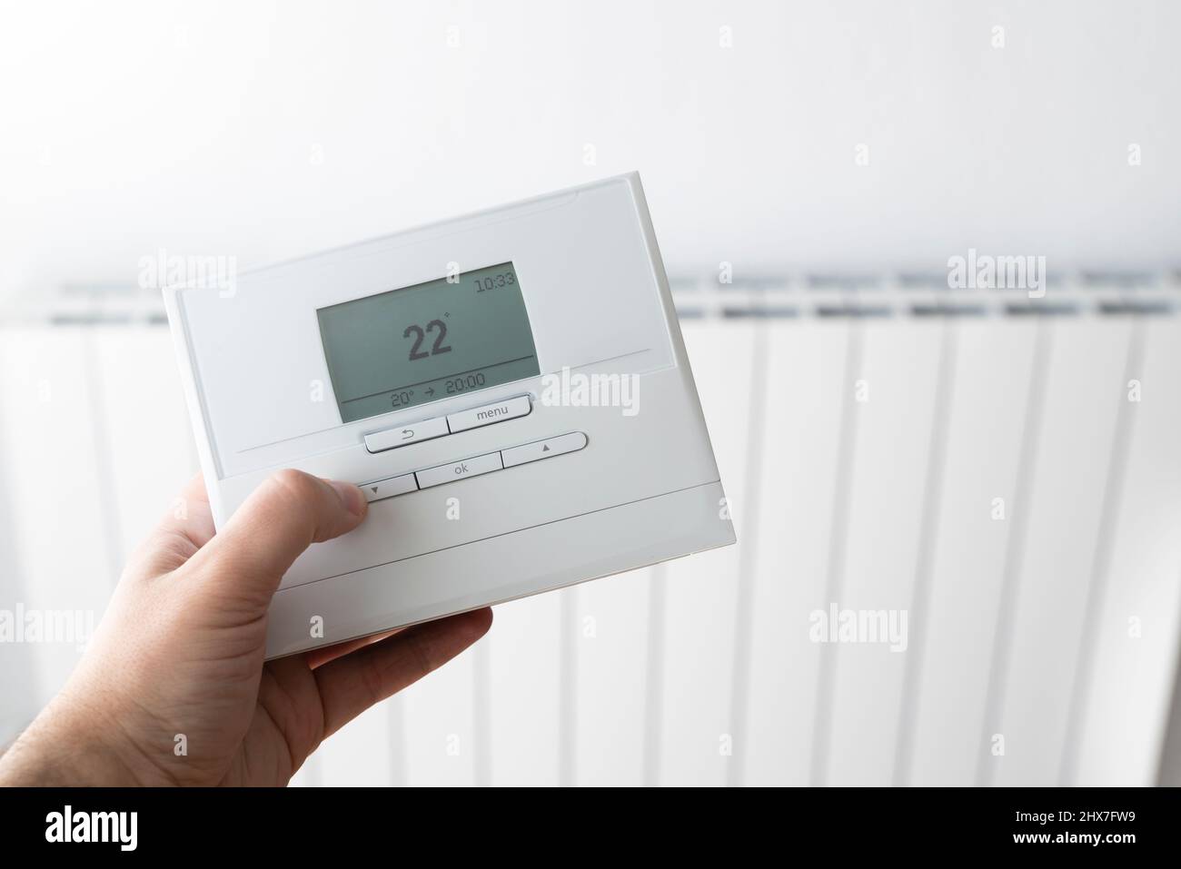 Abbassare la temperatura di riscaldamento per risparmiare denaro ed energia con un telecomando Foto Stock