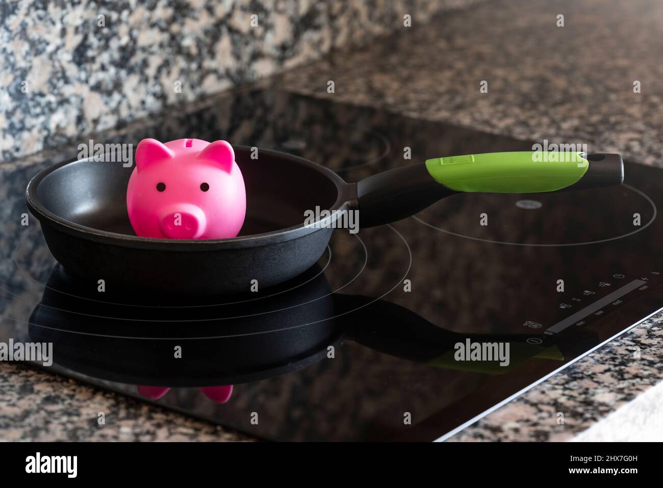 Concetto di risparmio di energia elettrica in una cucina con una banca di porcellini Foto Stock