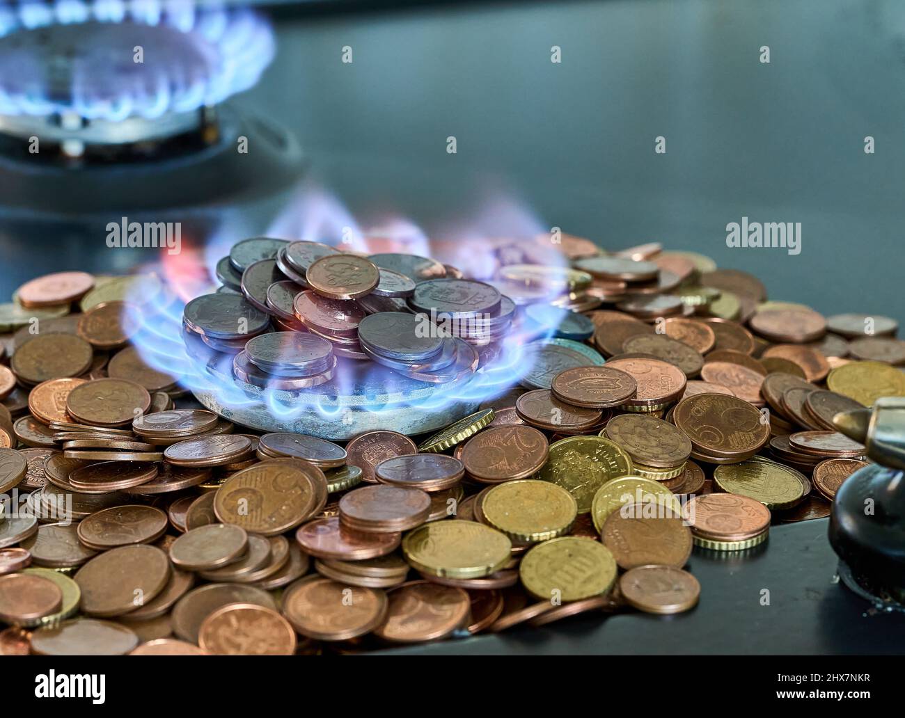 Monete metalliche in euro che bruciano nella stufa a gas Foto Stock