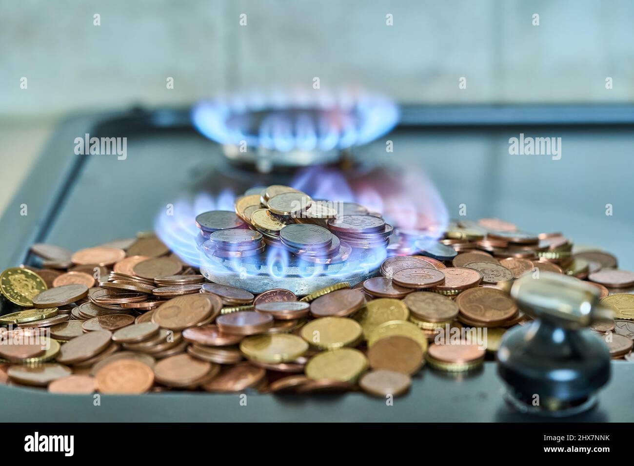 Monete metalliche in euro che bruciano nella stufa a gas Foto Stock