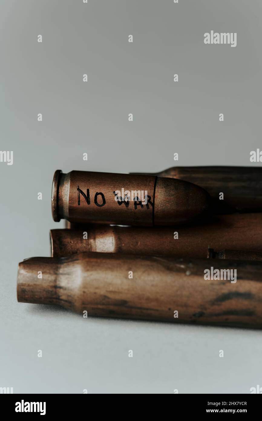alcuni proiettili usati su una superficie biancastra e un proiettile con il testo senza guerra scritto sopra di loro, con un po' di spazio vuoto sulla parte superiore Foto Stock