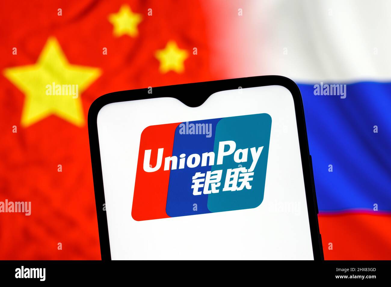 UnionPay è un sistema di trasferimento di denaro elettronico cinese in tutto il mondo. Logo UnionPay sullo schermo dello smartphone sullo sfondo delle bandiere di Cina e Russia. Foto Stock