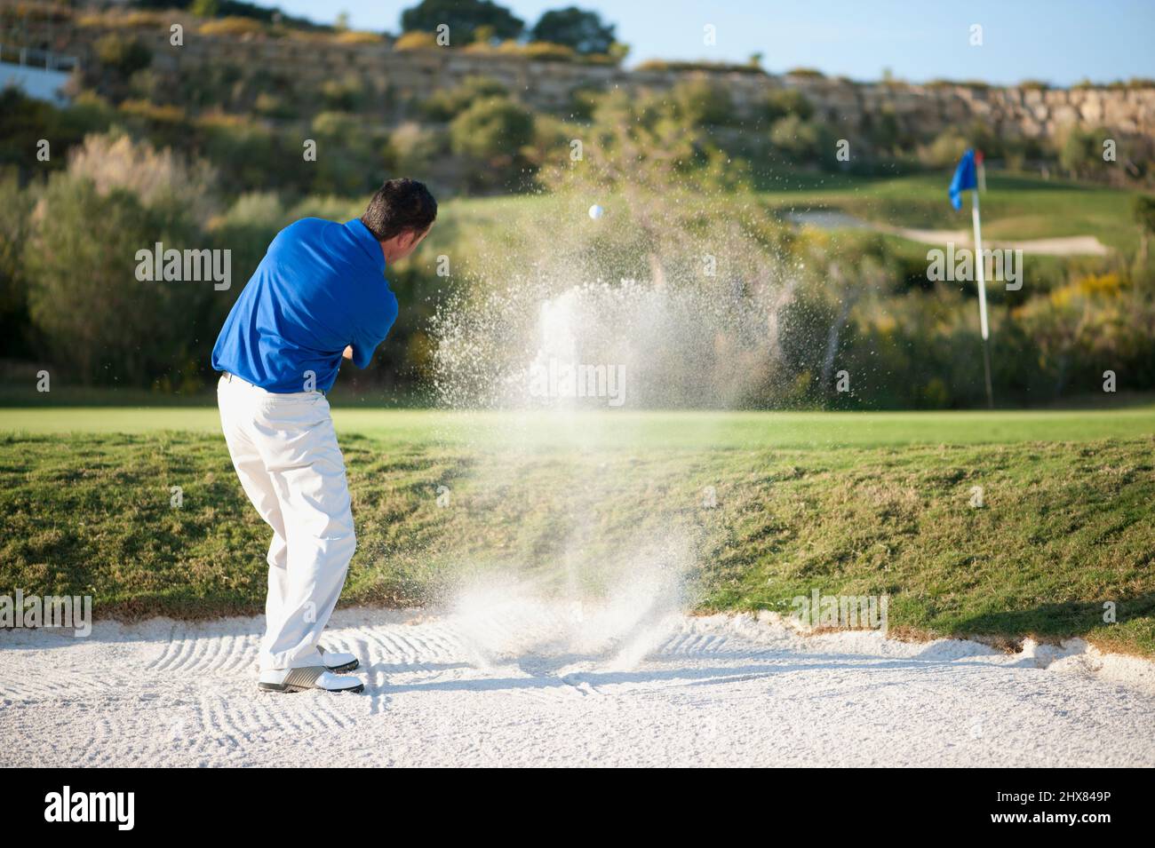 Palla colpisce il golfista da una trappola di sabbia Foto Stock