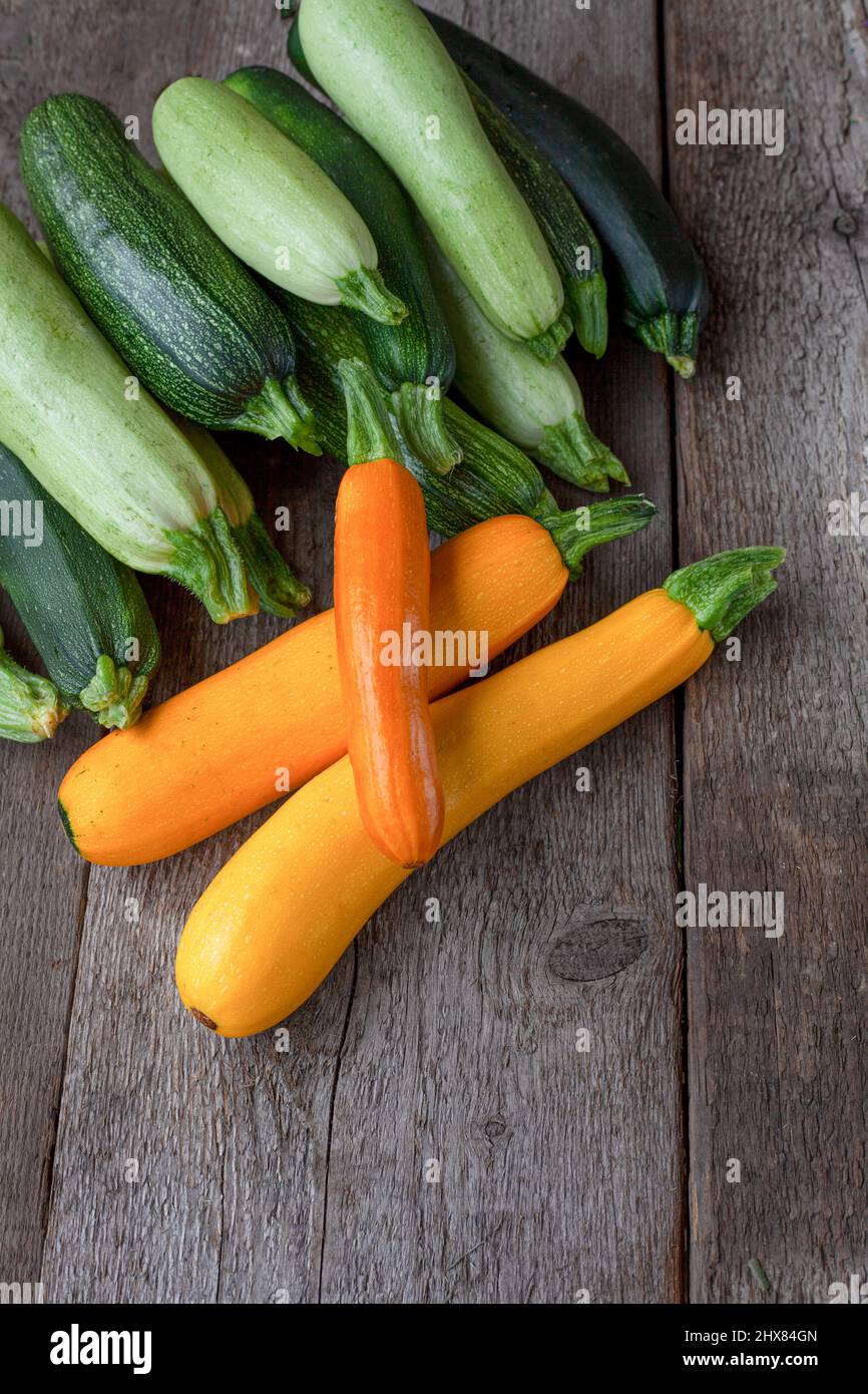 Una serie di zucchine multicolore gialle, verdi, bianche, arancioni sul tavolo da primo piano. Sfondo alimentare. Zucchine fresche raccolte, zucca estiva tagliata. Zucchine verdi selezionate. Ancora vita in cucina. Foto Stock