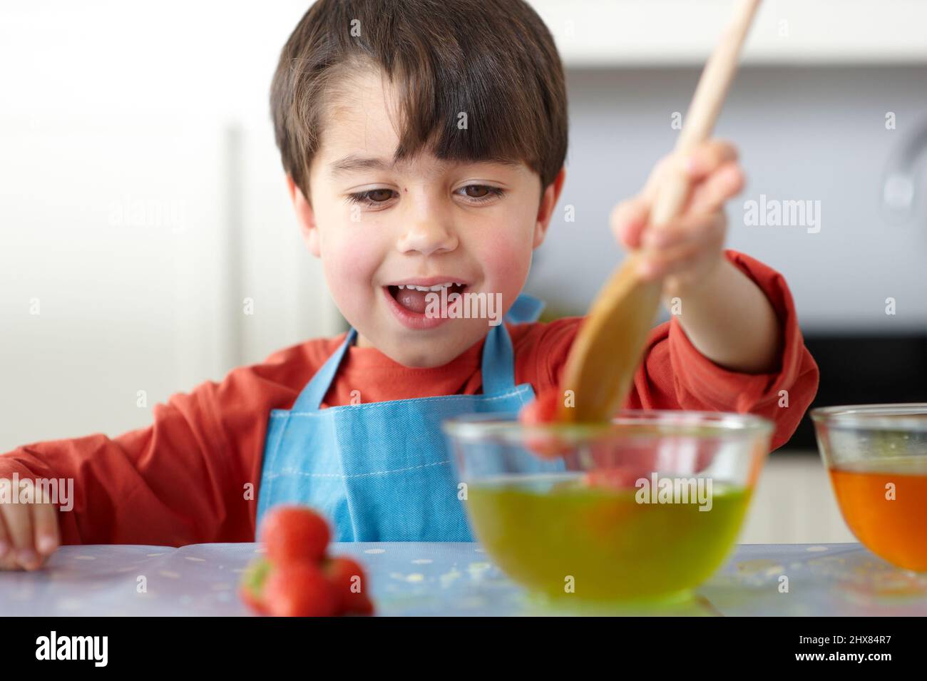Ragazzo che gocciola fragole in una ciotola di gelatina Foto Stock