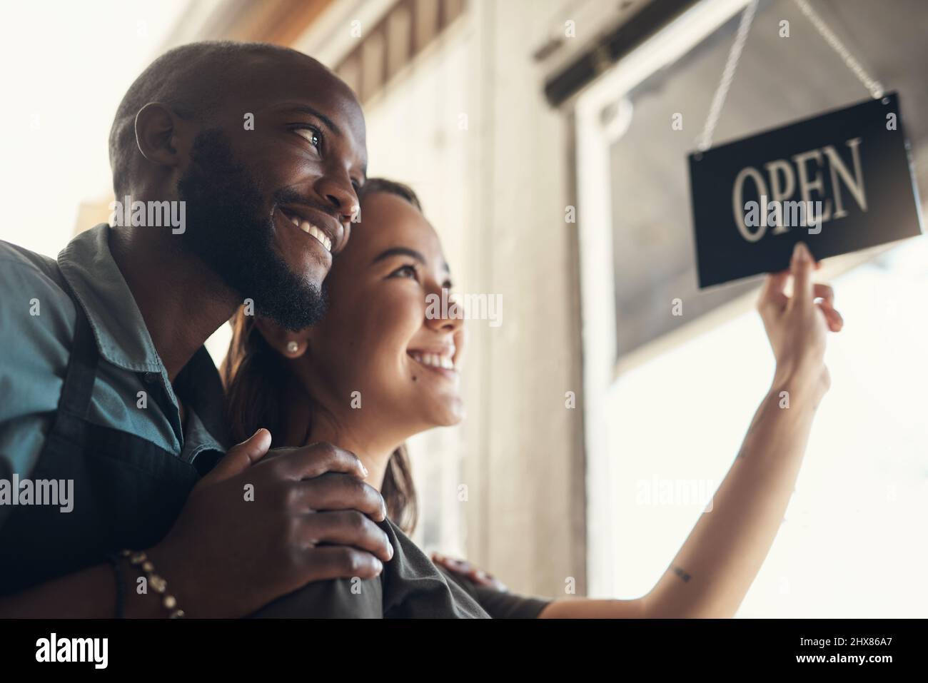 Siamo stati in per una giornata piena di impegni, babe. Scatto di una giovane coppia in piedi insieme e girare il cartello sulla porta per il loro negozio di biciclette. Foto Stock