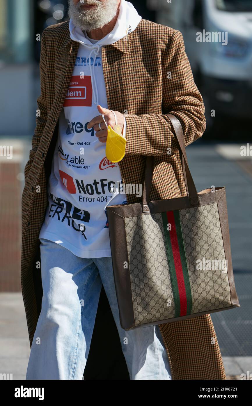 MILANO, ITALIA - 23 FEBBRAIO 2022: Uomo con borsa Gucci, marrone, cappotto  lungo e felpa bianca prima della sfilata di moda Marco Rambaldi, Milano  Fashion Week Street Foto stock - Alamy