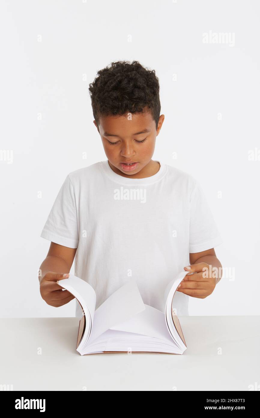 Bambino che guarda le pagine all'interno di due notebook come parte di un test di attrito. Modello età 8. Foto Stock