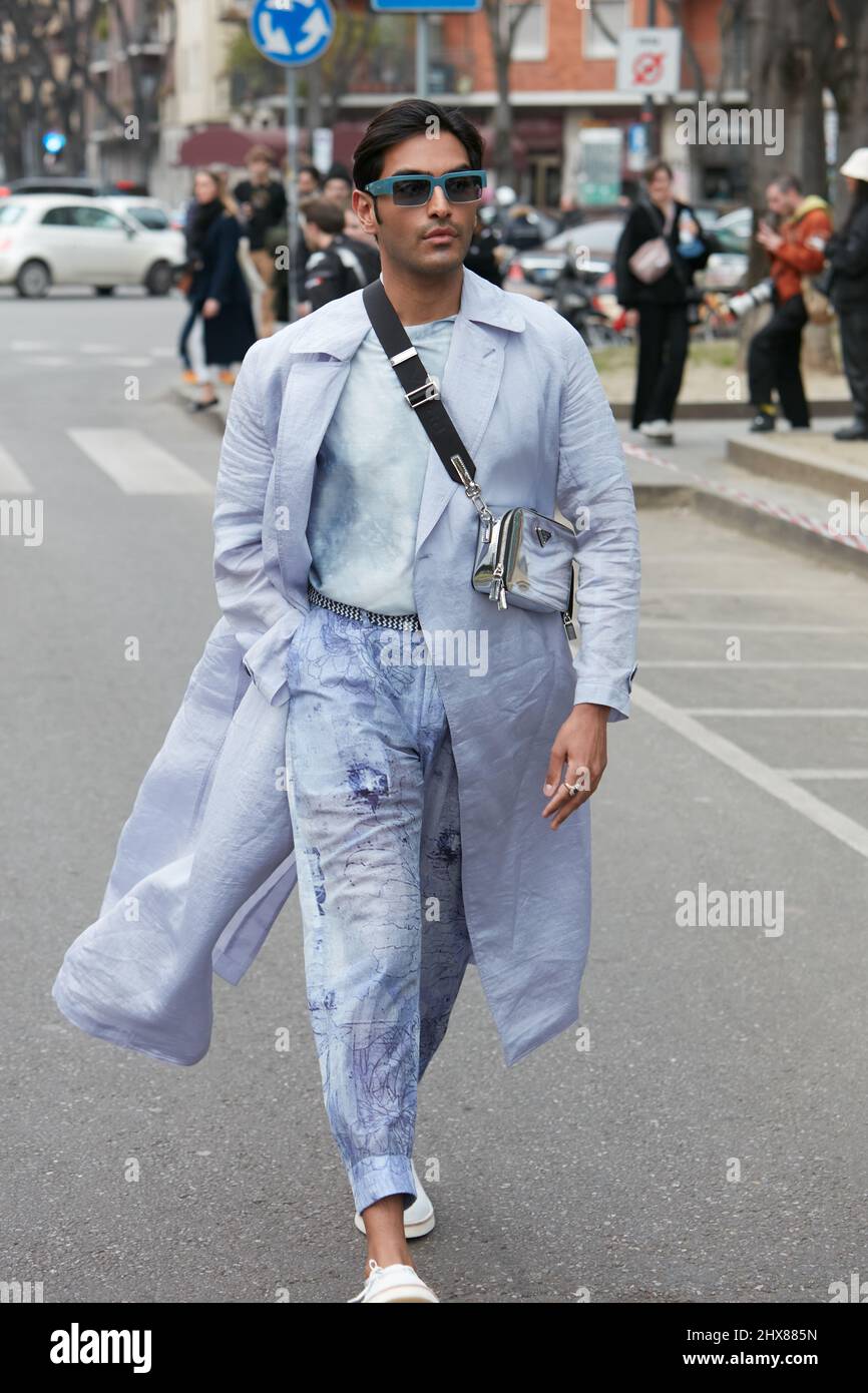 MILANO, ITALIA - 24 FEBBRAIO 2022: Uomo con trench viola pallido e pantaloni e borsa Prada argento prima della sfilata di moda Emporio Armani, Milano Fashion Foto Stock