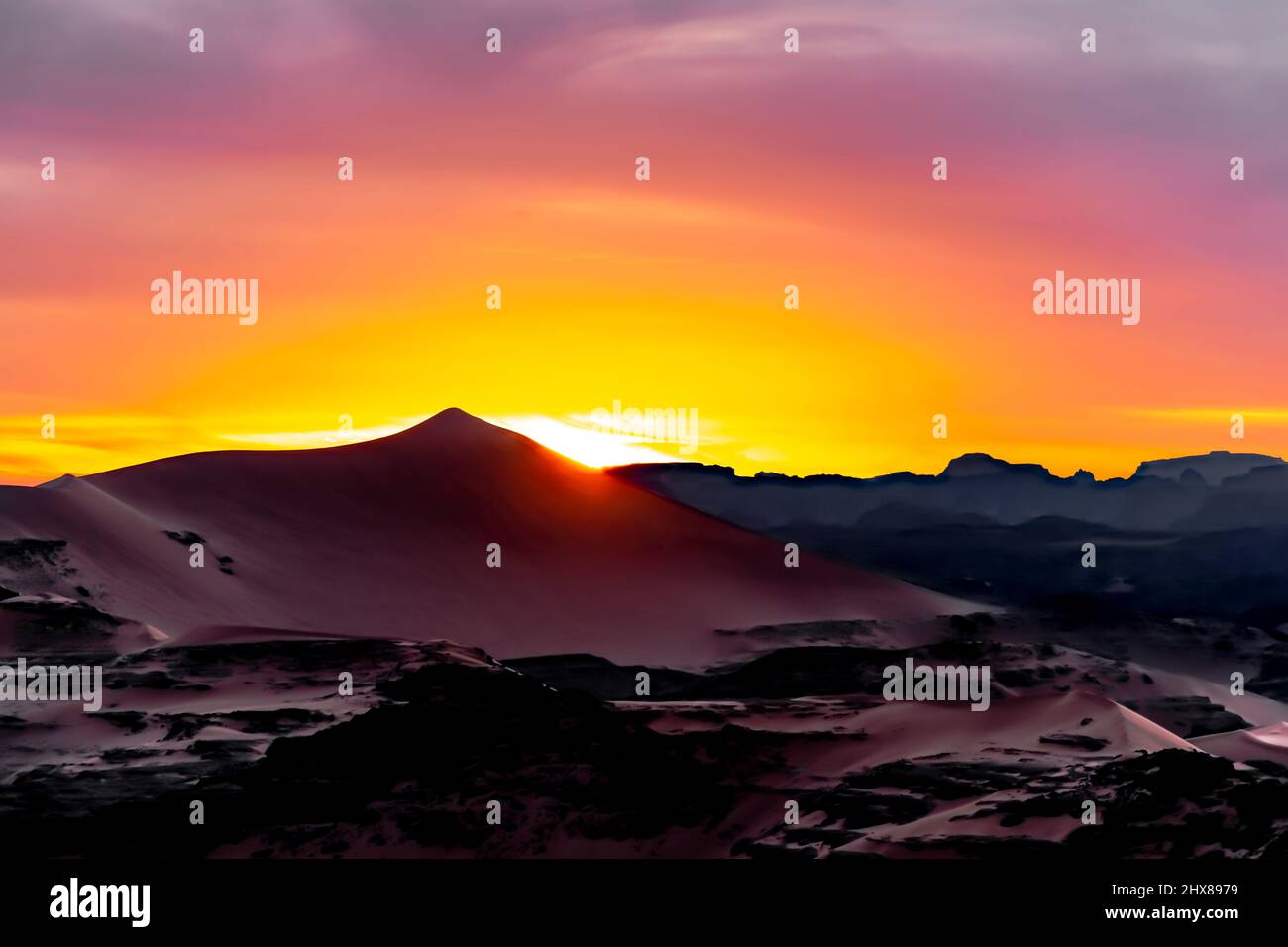 Tramonto colorato dietro un enorme paesaggio di dune di sabbia. Vista aerea dalla cima di una duna di sabbia di Montagne Rocciose e cielo nuvoloso multicolore. Foto Stock