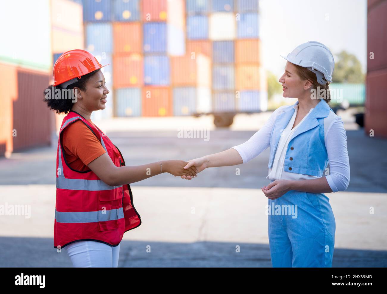 Attività di magazzino. Una donna Africana americana uomo e una donna CEO in tuta scuotono le mani e concludono un lavoro per il trasporto e la logistica dopo il successo Foto Stock