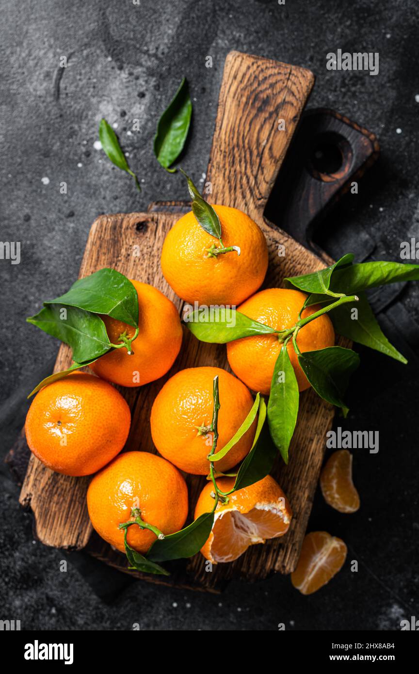 Mandarino arance o mandarino frutta con foglie su tavola di legno. Sfondo nero. Vista dall'alto Foto Stock