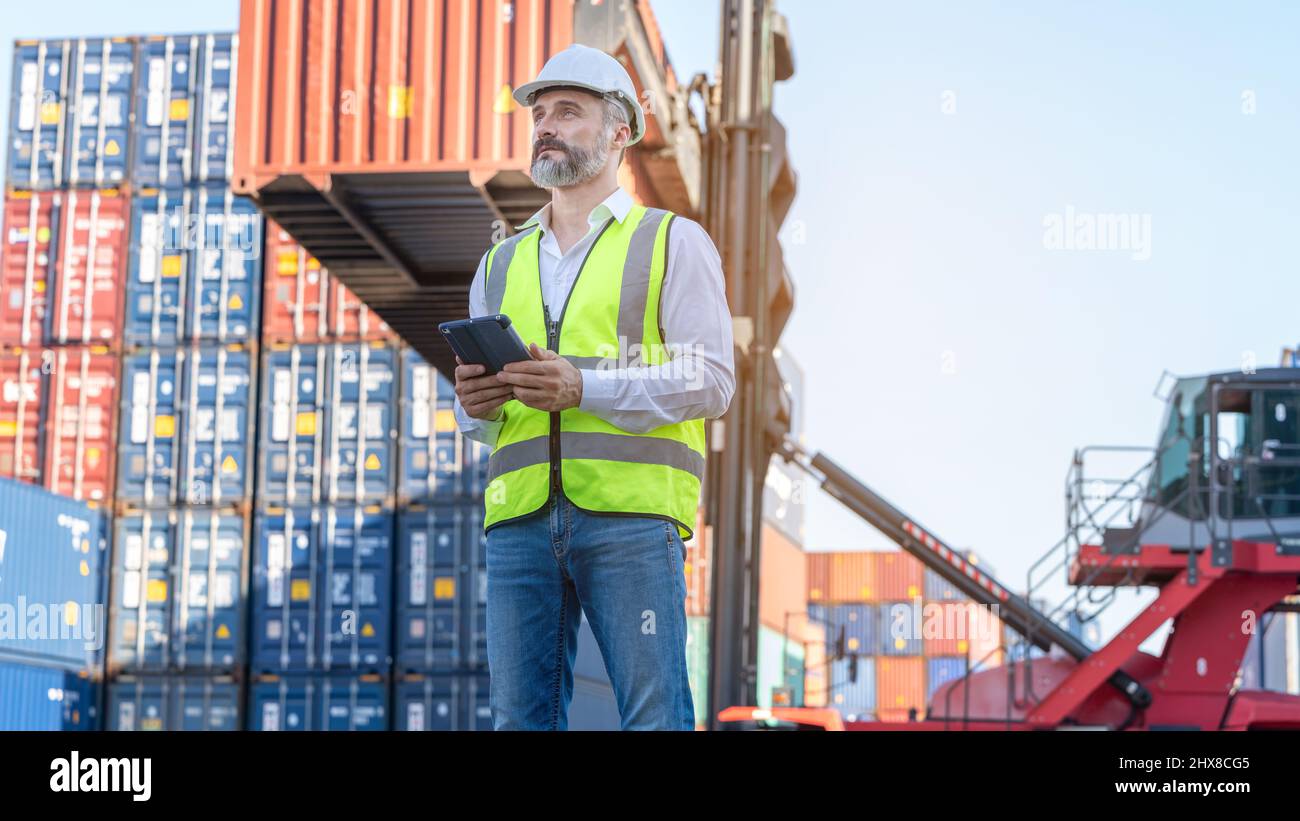 CEO o Manager in casco bianco con controllo tablet caricamento contenitori in magazzino , responsabile ispettore o supervisore di sicurezza in Container CustomTer Foto Stock