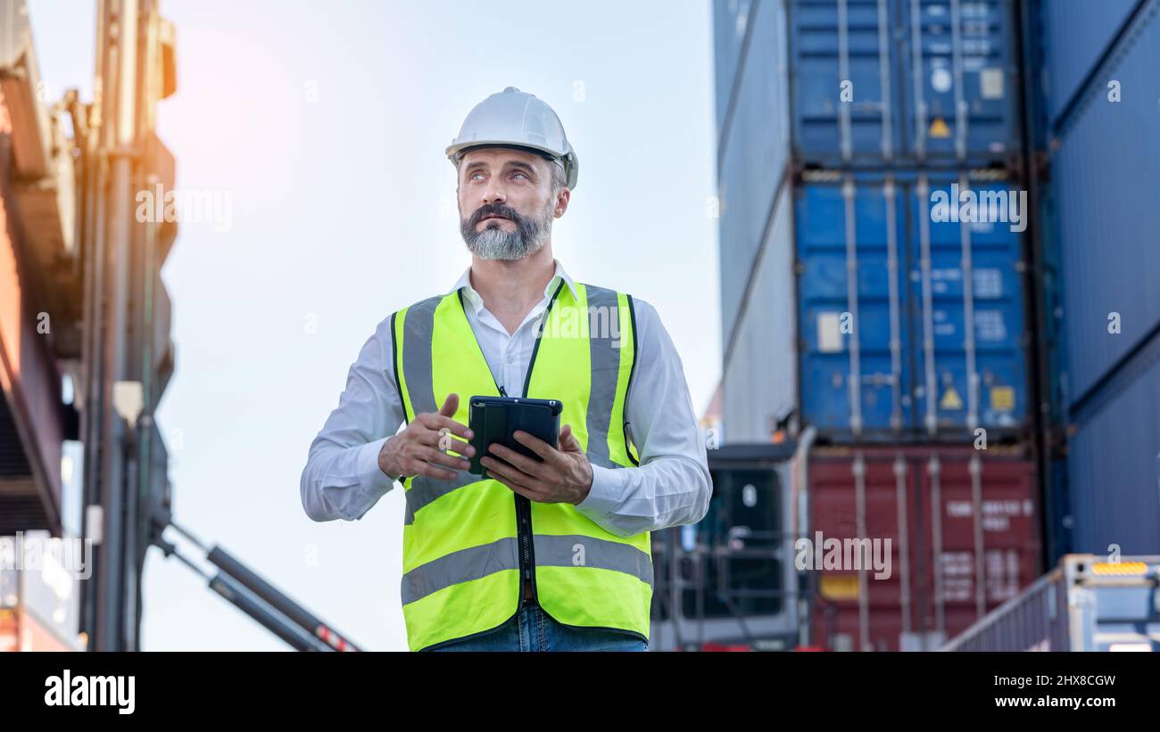 CEO o Manager in casco bianco con controllo tablet caricamento contenitori in magazzino , responsabile ispettore o supervisore di sicurezza in Container CustomTer Foto Stock
