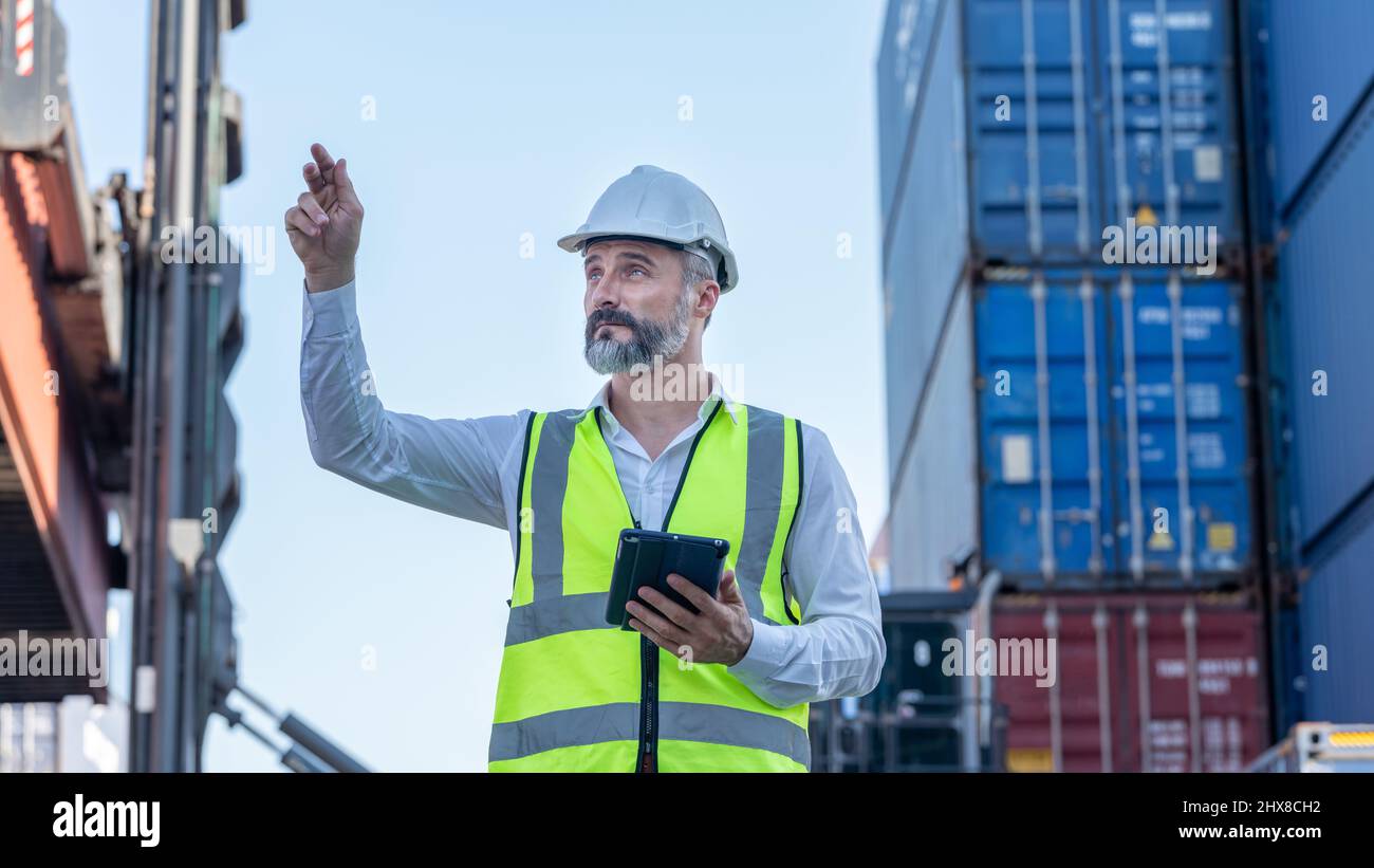CEO o Manager in casco bianco con controllo tablet caricamento contenitori in magazzino , responsabile ispettore o supervisore di sicurezza in Container CustomTer Foto Stock