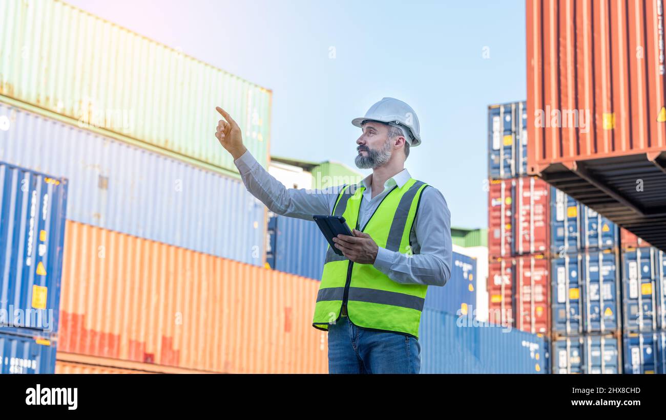 CEO o Manager in casco bianco con controllo tablet caricamento contenitori in magazzino , responsabile ispettore o supervisore di sicurezza in Container CustomTer Foto Stock