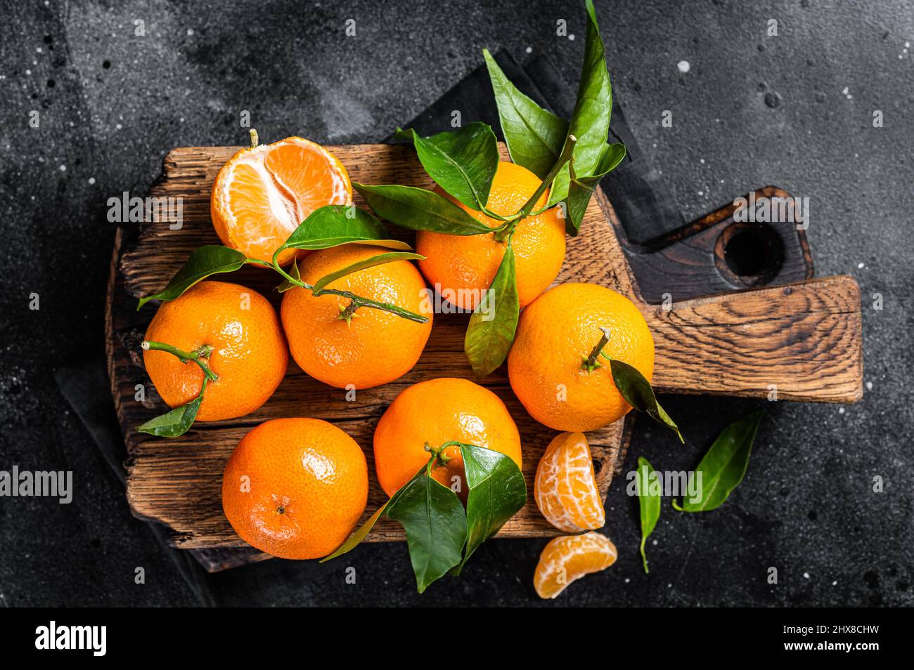 Mandarino arance o mandarino frutta con foglie su tavola di legno. Sfondo nero. Vista dall'alto Foto Stock