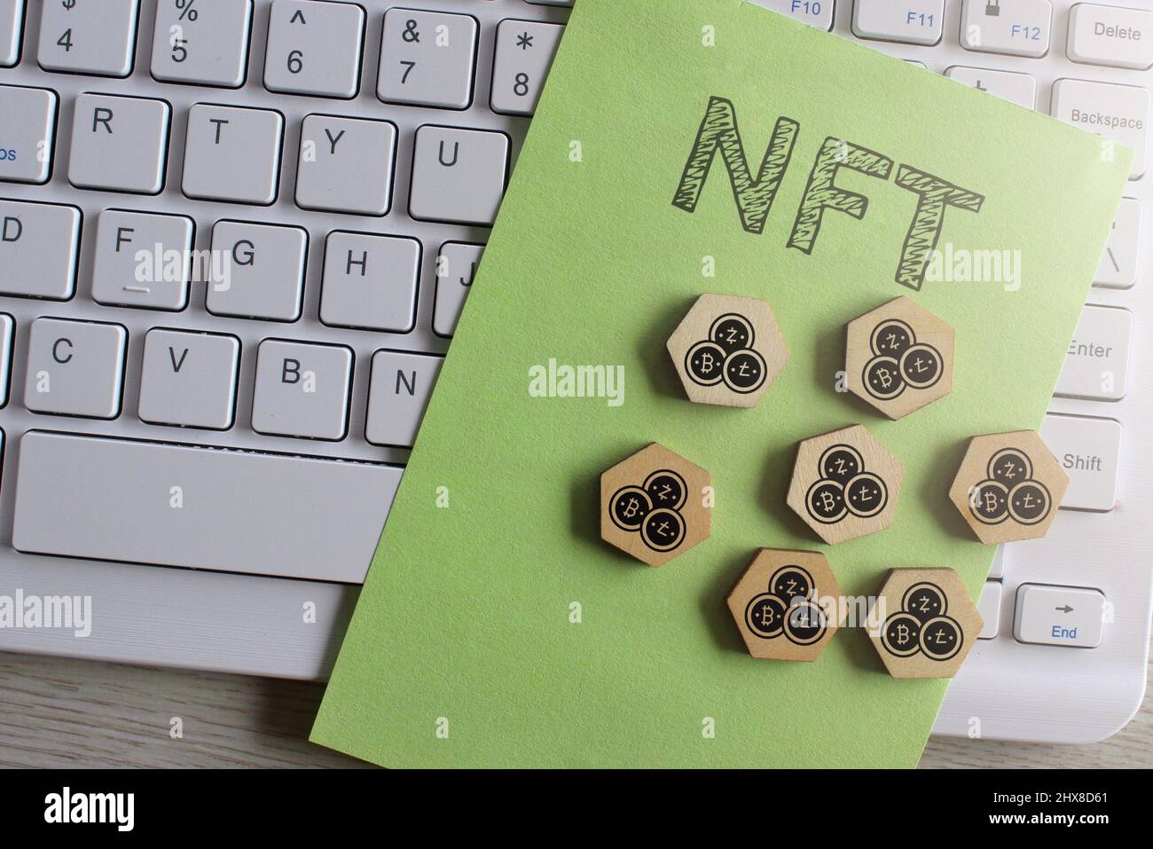 Immagine vista dall'alto della tastiera, carta con testo NFT ed esagono in legno con icona criptovaluta. Foto Stock