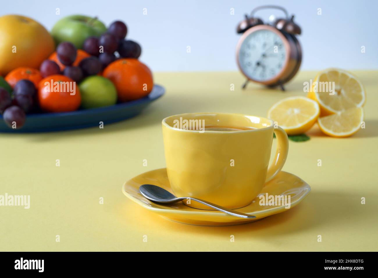 Colazione di una persona che si preoccupa della sua salute - frutta, una bevanda calda. Sfondo giallo per una grande mattinata di sole Foto Stock