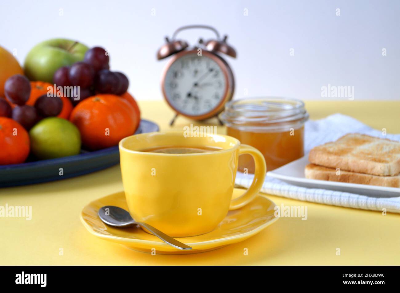 A colazione, al tavolo c'è una tazza di tè, pane tostato con miele e frutta. Foto Stock