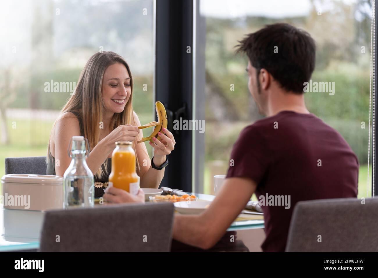 Giovane coppia che ha fatto colazione nel soggiorno di casa vicino al giardino Foto Stock