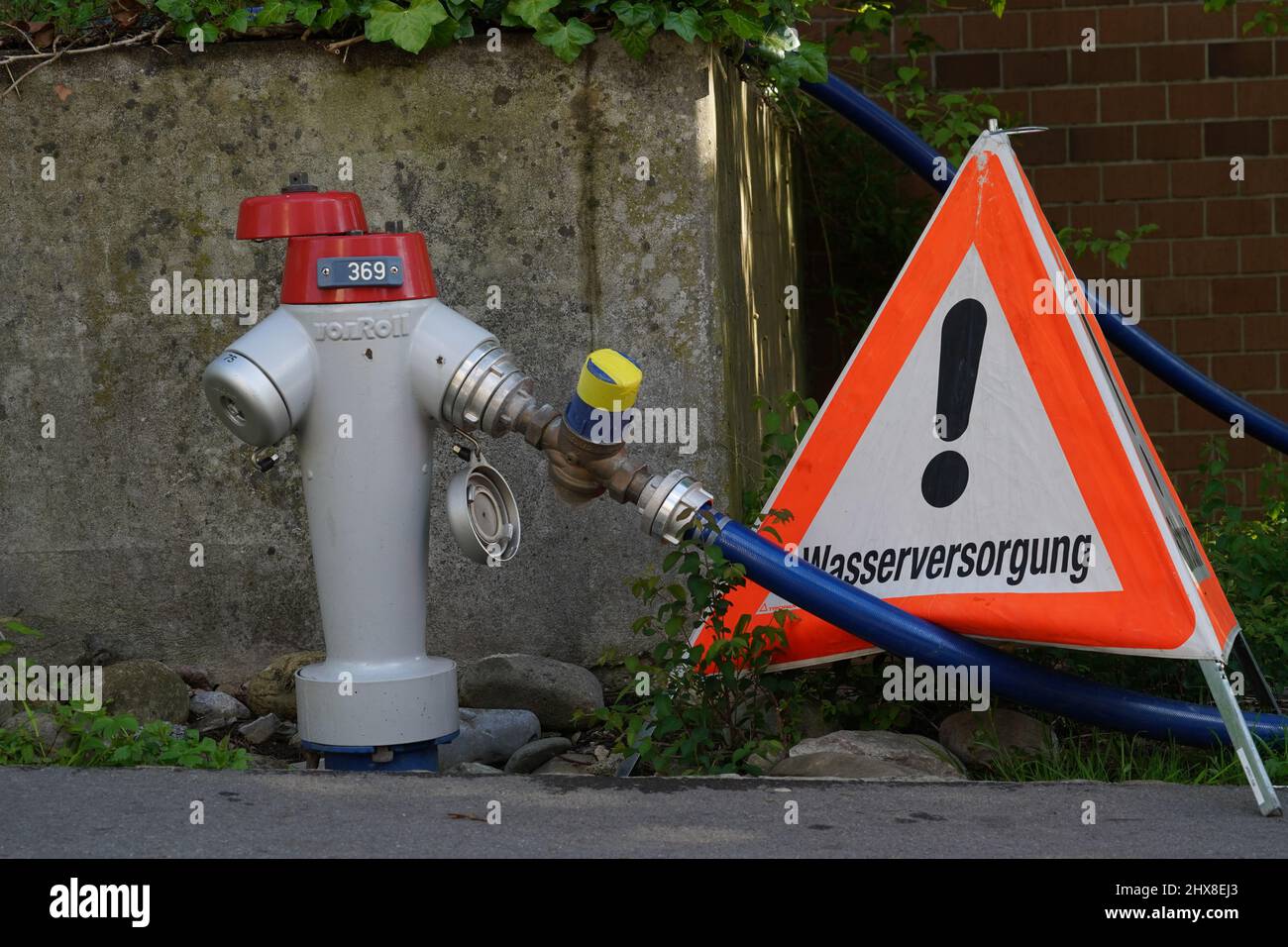 Urdorf, Svizzera 05 27 2021 idrante d'acqua in strada con un triangolo d'allarme con parola tedesca che significa tubo rotto. Foto Stock