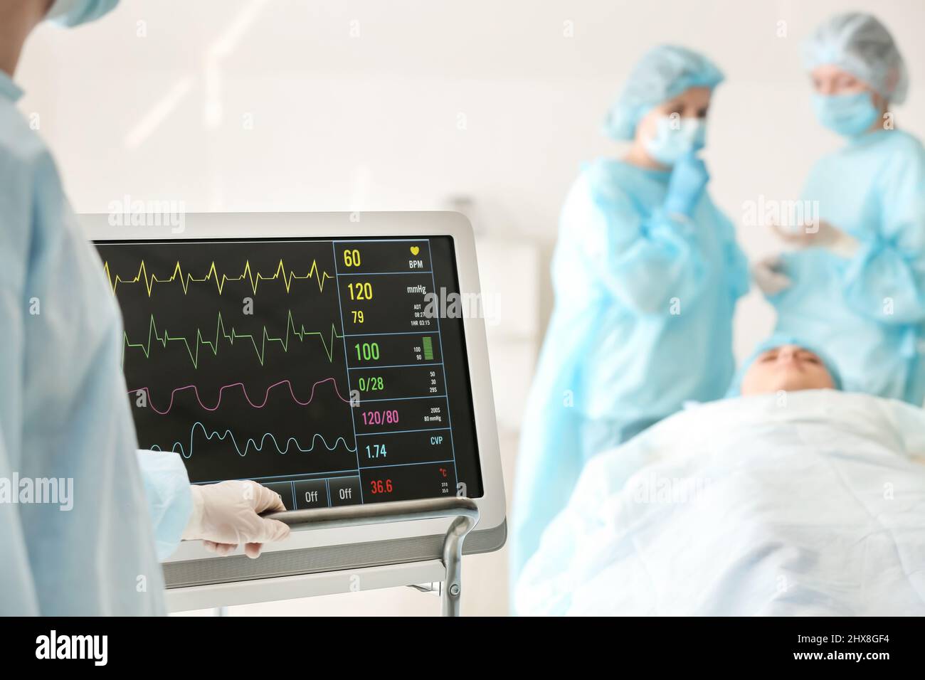 Medico vicino al monitor della frequenza cardiaca moderno in sala operatoria Foto Stock