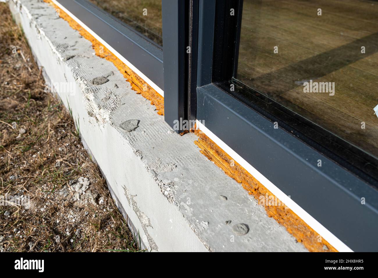 Vecchia schiuma di montaggio gialla sotto una grande finestra terrazza, visibile styrofoam che isola le fondamenta della casa. Foto Stock