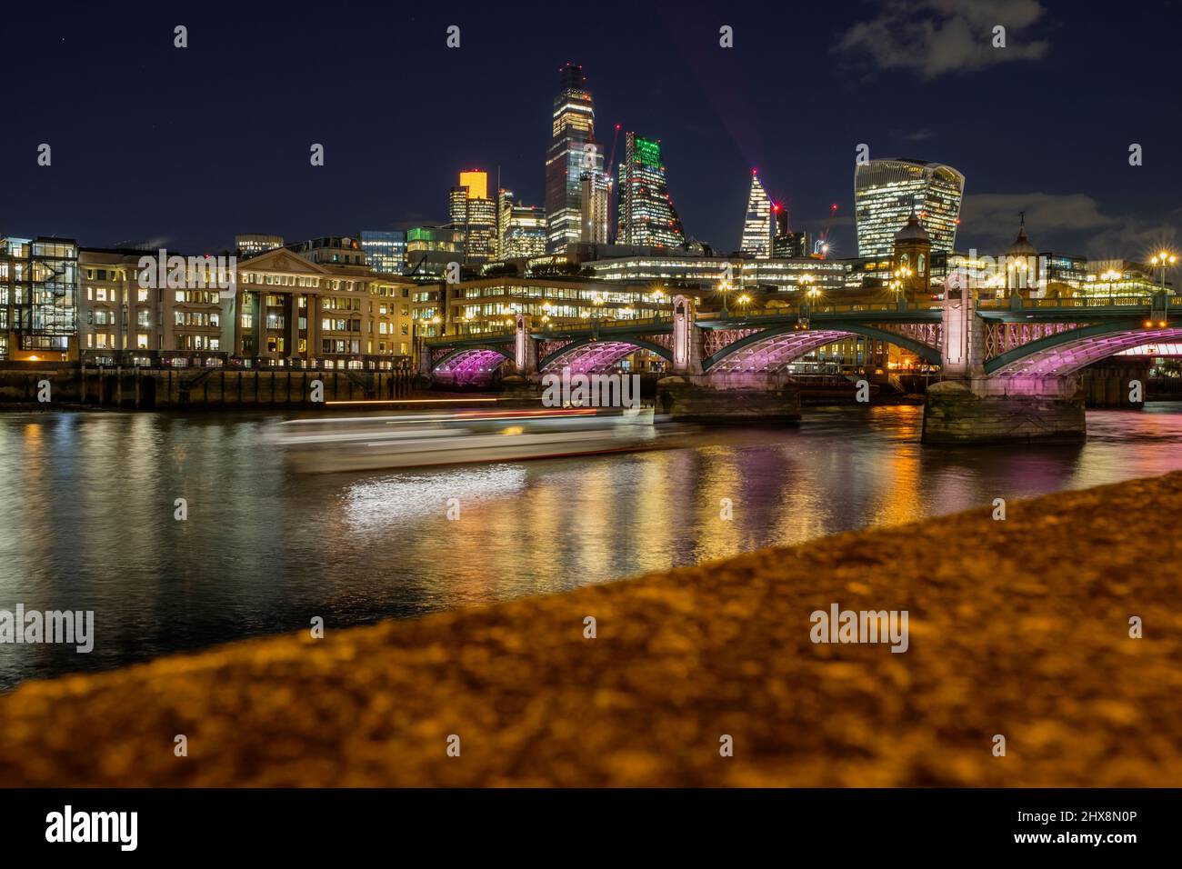 Foto lunga esposizione del ponte Southwark con una barca Uber. Foto Stock