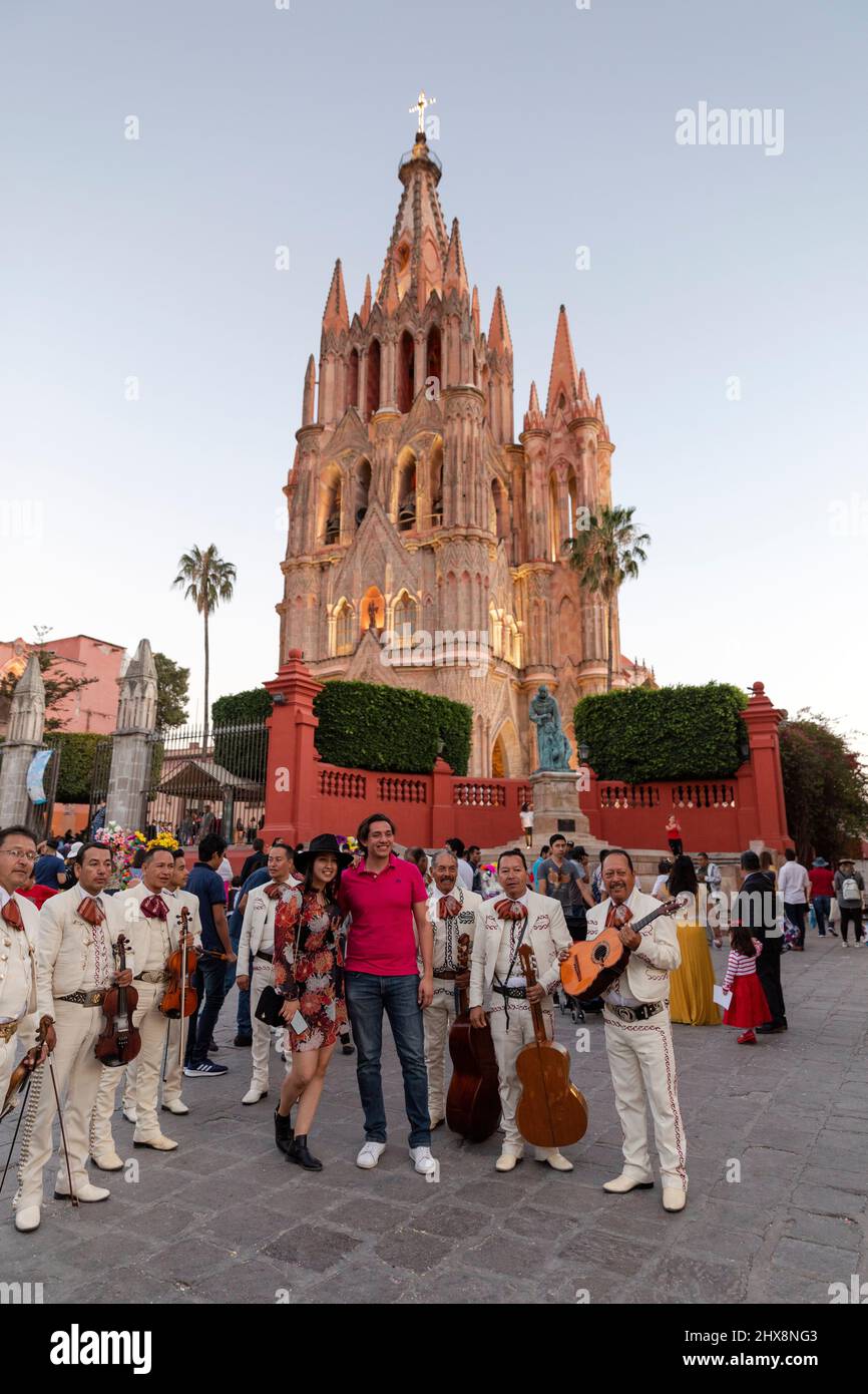 Messico, Stato di Guanajuato, San Miguel de Allende, coppia in posa con una banda di mariachi di fronte alla Parroquia de San Miguel Arcangel. Foto Stock