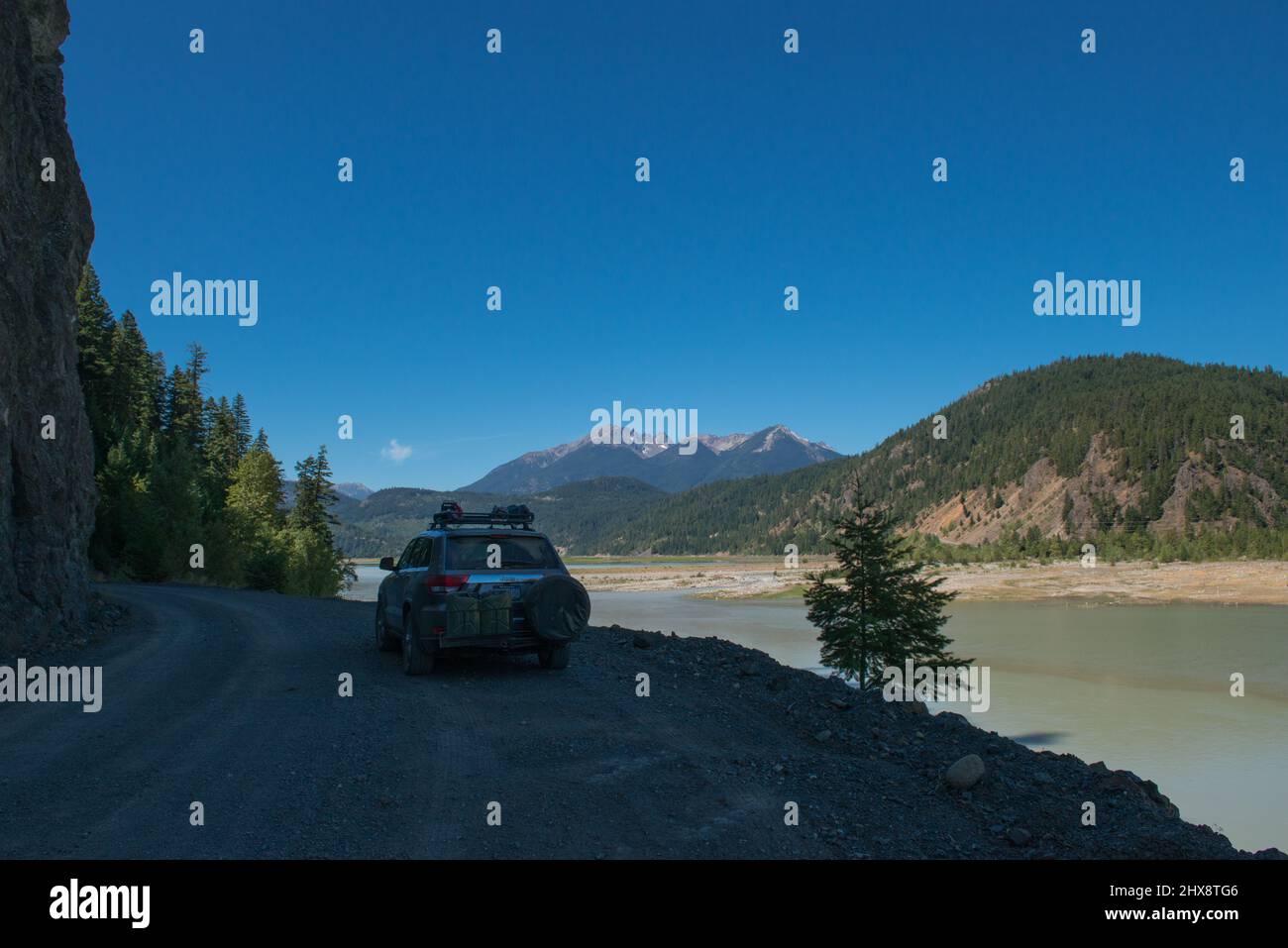 Auto dotata di ruota di scorta e taniche di carburante per la guida fuoristrada su strade strette di ghiaia lungo le montagne e il lago nella Columbia Britannica, Canada Foto Stock