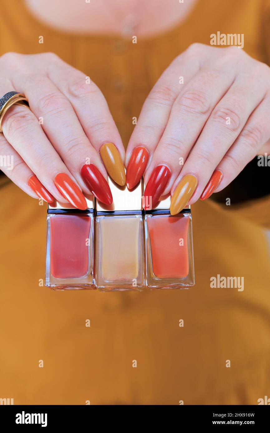 Donna bella mano con unghie lunghe e un giallo arancio unghie lucidare e  foglie di acero autunno Foto stock - Alamy