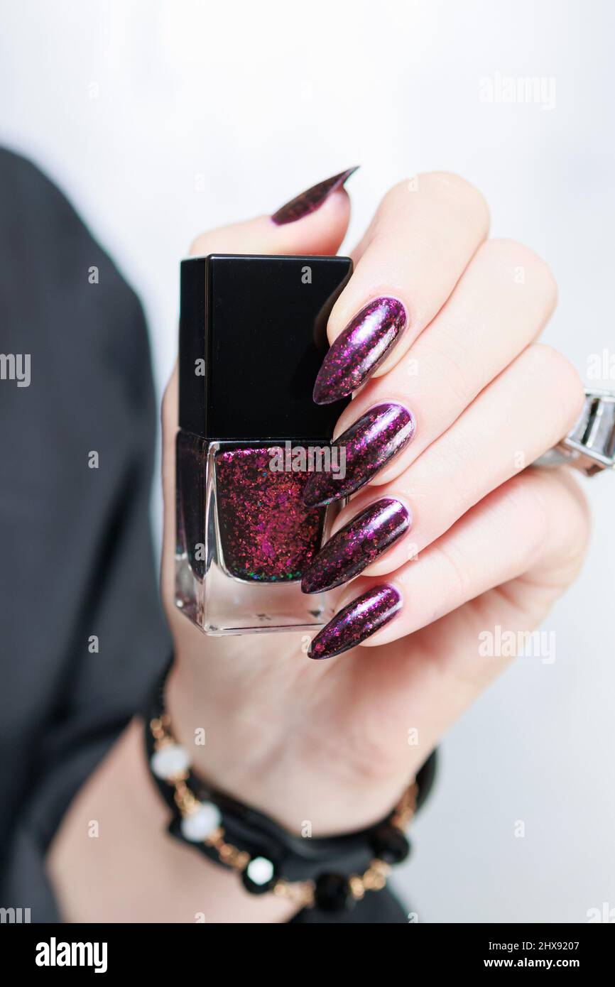 Mani femminili con unghie lunghe e manicure viola borgogna che tiene una  bottiglia di smalto per unghie Foto stock - Alamy
