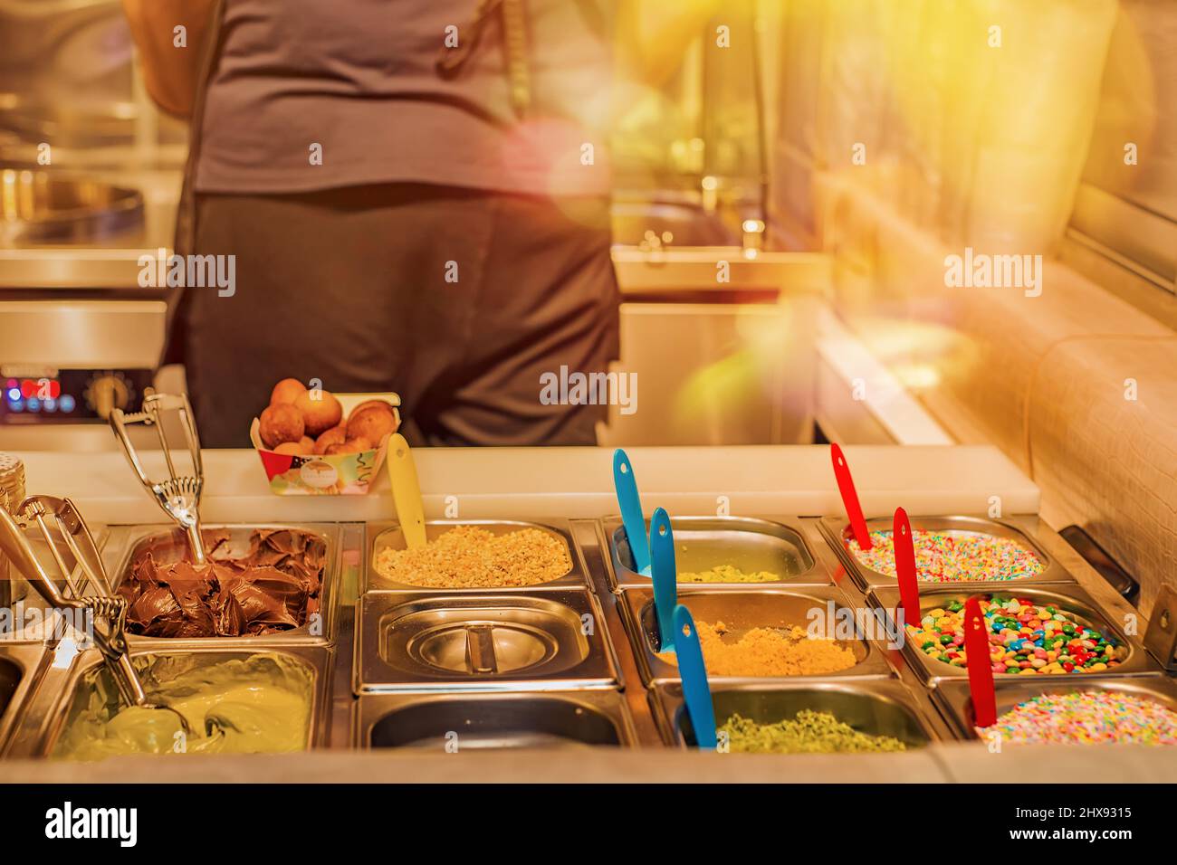 Le ciambelle fritte fresche cospargono di sughero per le ciambelle in un bar sulla strada Foto Stock