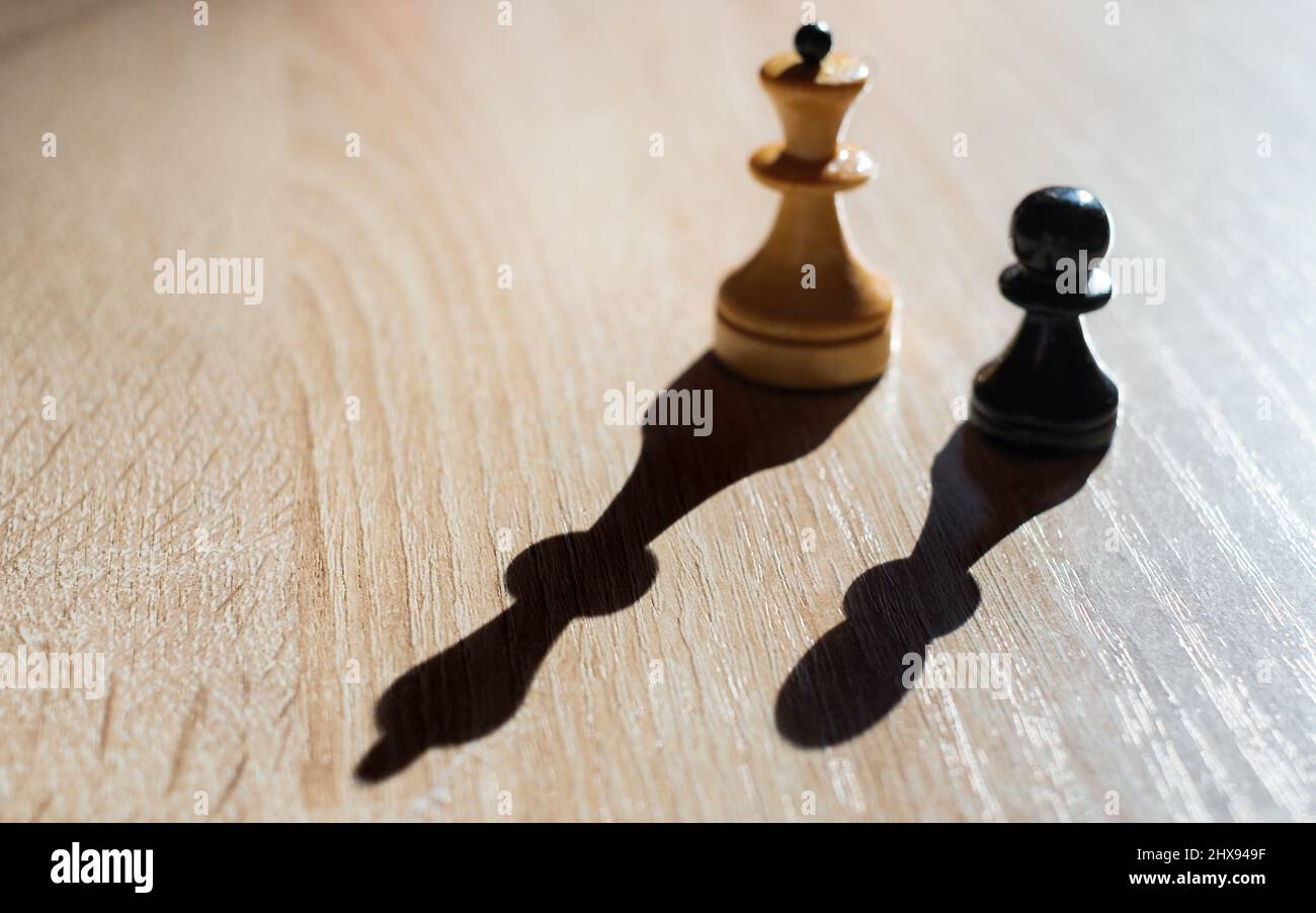 I pezzi sfocati di scacchi pedina e regina gettano ombre chiare. Concetto aziendale di crescita aziendale, tenendo conto della strategia e delle tattiche aziendali. BA Foto Stock