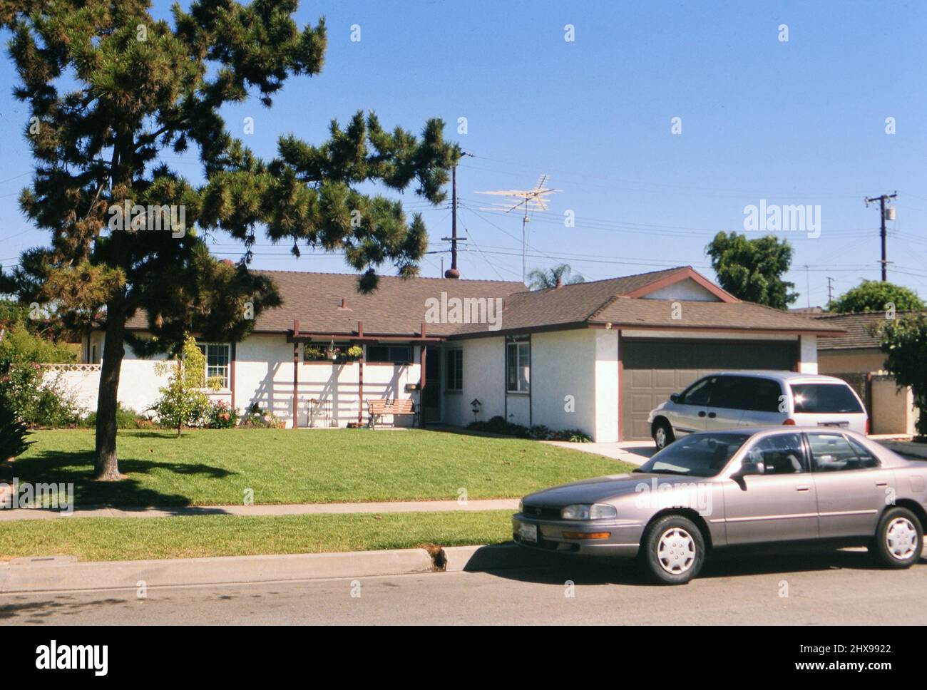 Un'auto e un minivan parcheggiati di fronte a una casa di classe media in un sobborgo americano ca. 2000 Foto Stock