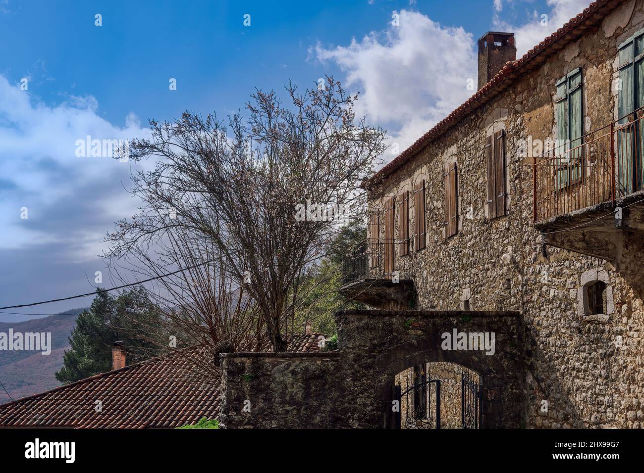 Tradizionale casa costruita in pietra contro il cielo blu con le nuvole. Vista ad angolo basso di giorno della vecchia residenza nel villaggio di Karytaina, in Arcadia Peloponneso Grecia. Foto Stock