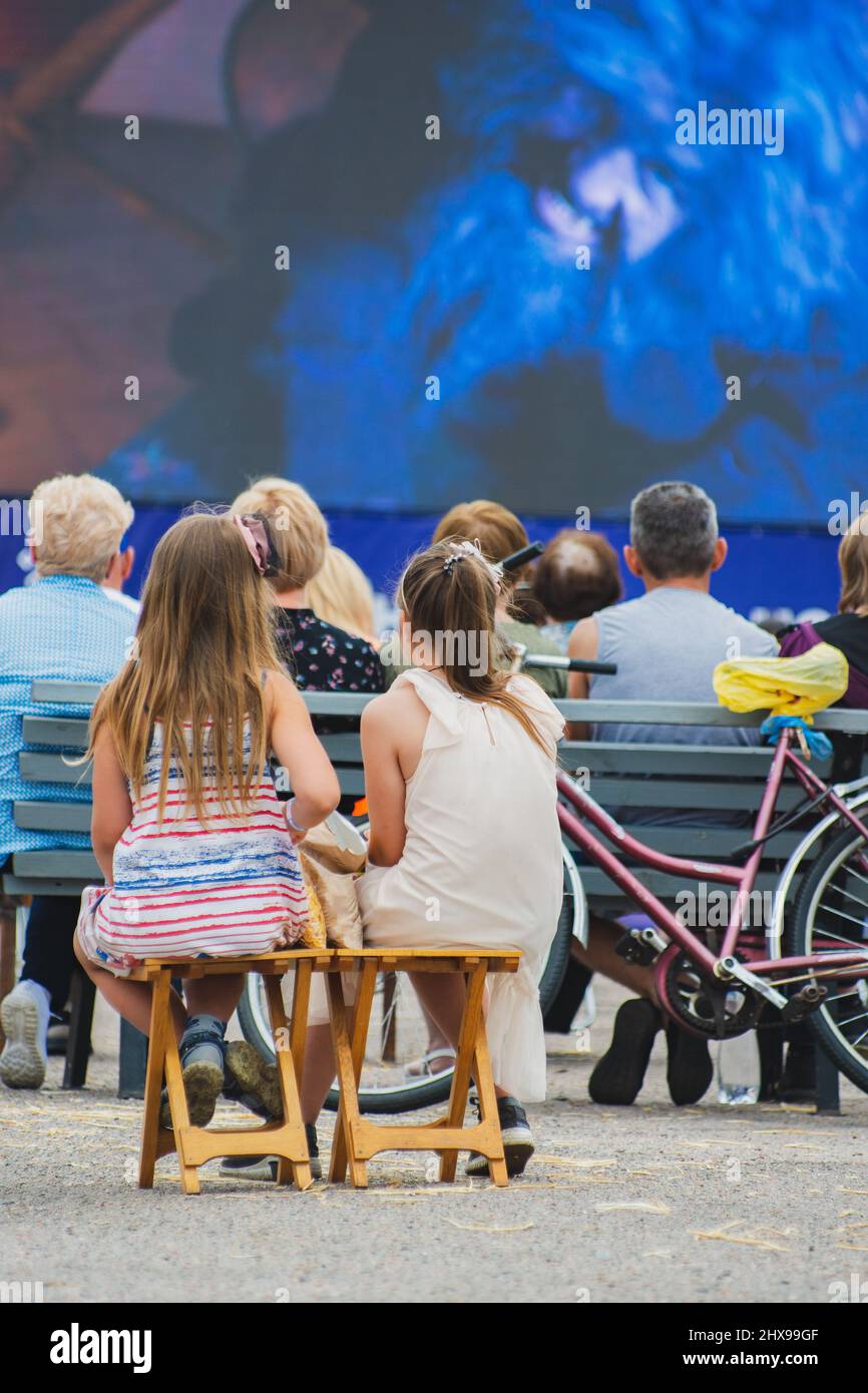 Cinema all'aperto. Persone che guardano un film su uno schermo cinematografico estivo. Foto Stock