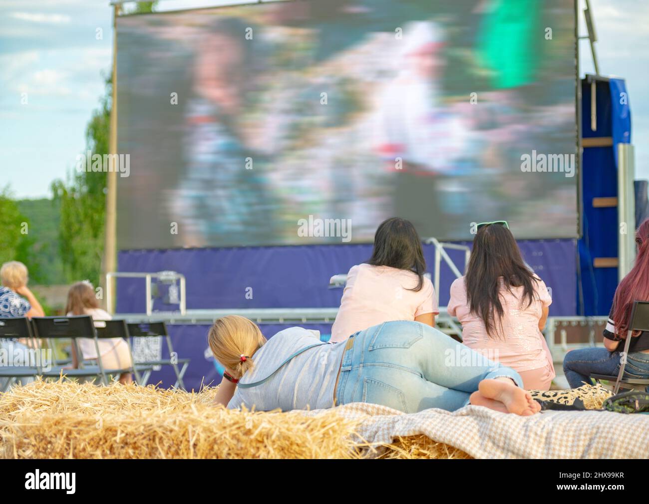 Cinema estivo. Persone e coppie che guardano un film sullo schermo di un cinema estivo la sera. Foto Stock