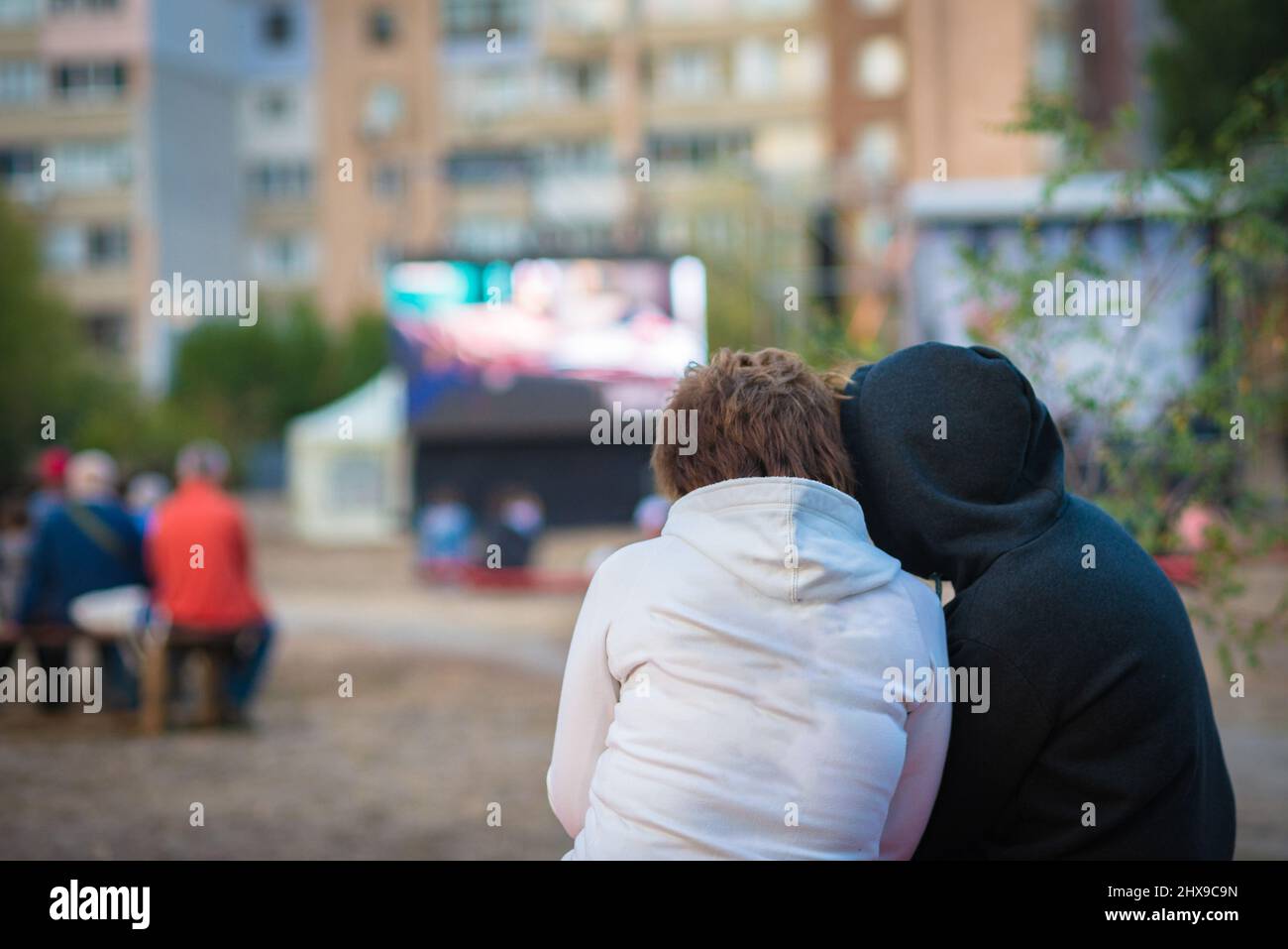 Cinema all'aperto. Persone che guardano un film su uno schermo cinematografico estivo. Foto Stock