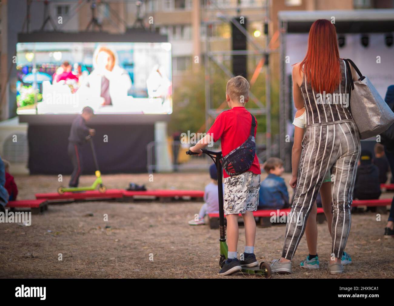 Cinema all'aperto. Persone che guardano un film su uno schermo cinematografico estivo. Foto Stock