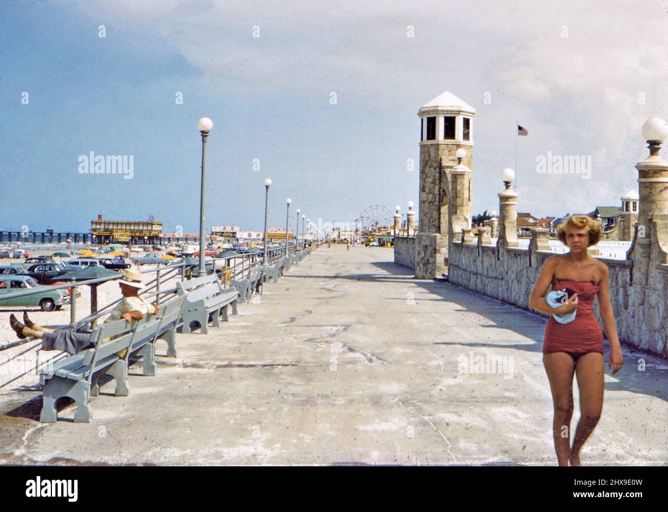 Donna in costume da bagno camminando lungo la passerella di cemento in Florida città innentificata ca. 1950s Foto Stock
