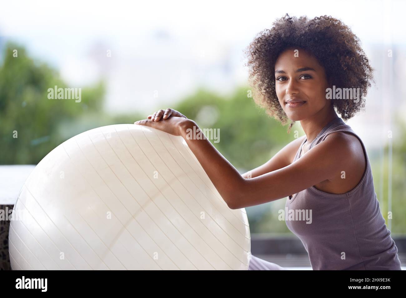 Solo io e la mia palla da esercizio. Ritratto corto di una giovane donna attraente seduta con una sfera di esercitazione. Foto Stock