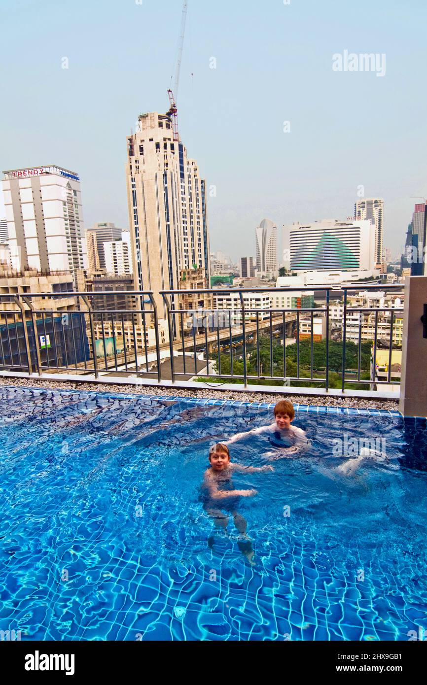 I ragazzi sono il nuoto in una piscina all'aperto con splendida vista per i grattacieli Foto Stock