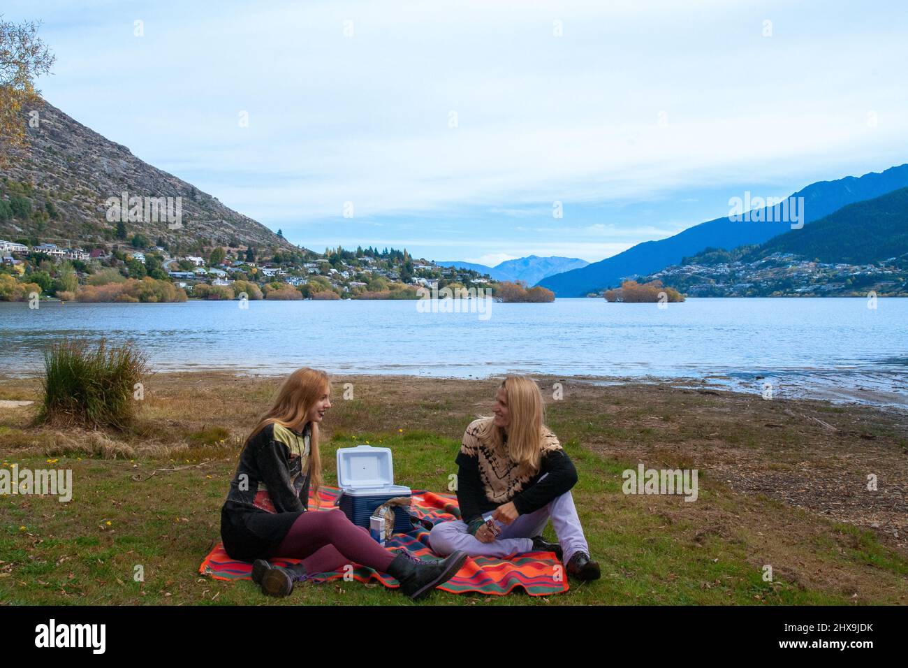 Coppia felice di viaggiatori hanno tempo romantico e picnic all'aperto a Queenstown Lake Wakatipu, Isola del Sud della Nuova Zelanda Foto Stock