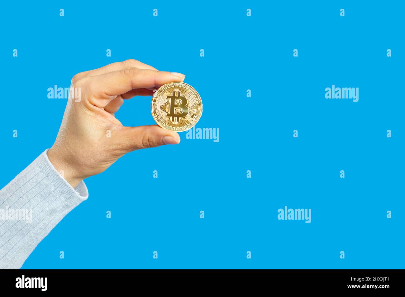 Moneta di tenuta umana con simbolo di bitcoin isolato su sfondo bianco blu dello spazio di copia Foto Stock