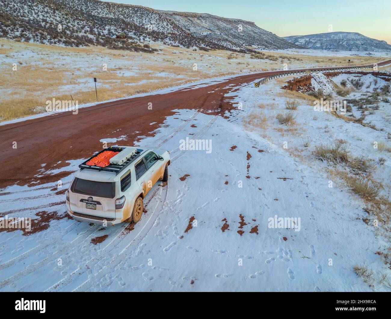 Fort Collins, CO, Stati Uniti d'America - 17 febbraio 2022: Dirty Toyota 4Runner SUV su una strada di ranch fangoso al tramonto d'inverno ai piedi delle colline del Colorado, vedendo aerea Foto Stock